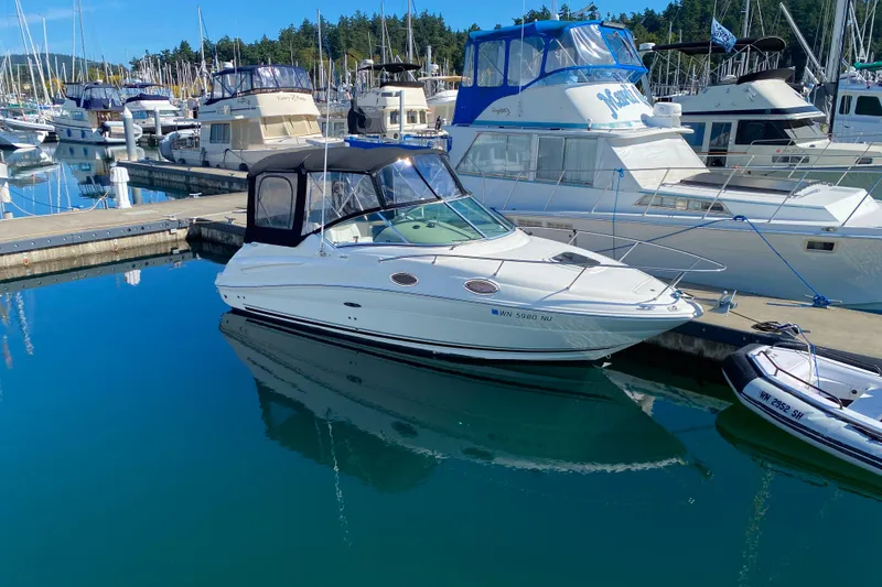 Slide: The Image of 2006 Sea Ray 240 Sundancer docked in a marina, surrounded by other boats. - 28