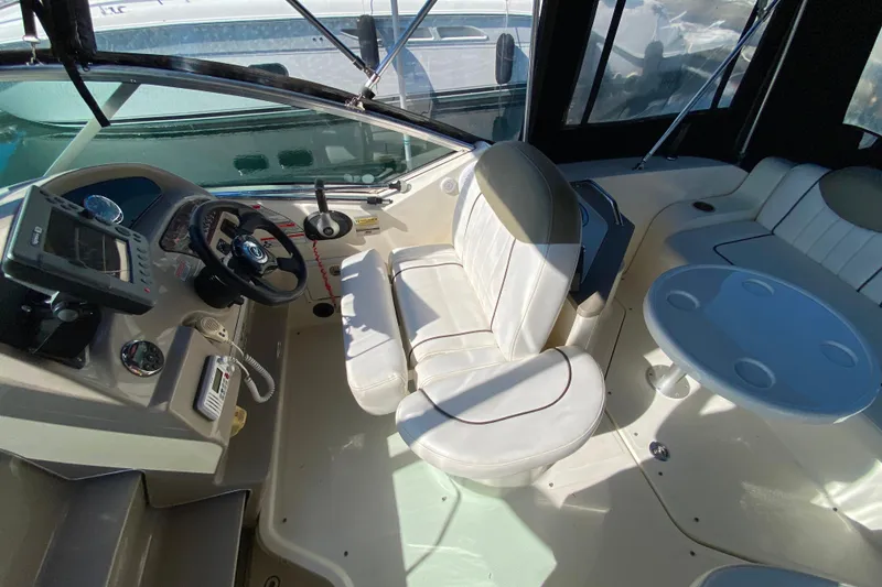 Slide: The Image of 2006 Sea Ray 240 Sundancer boat interior with helm, seating, and table. - 5