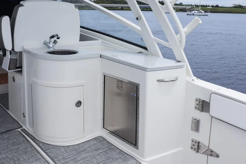 Slide: The Image of 2026 World Cat 325DC boat interior with sink and storage, docked by the water. - 23