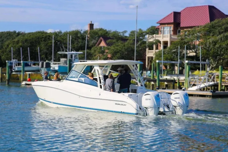 Slide: The Image of 2026 World Cat 325DC boat cruising near a marina with passengers onboard. - 3