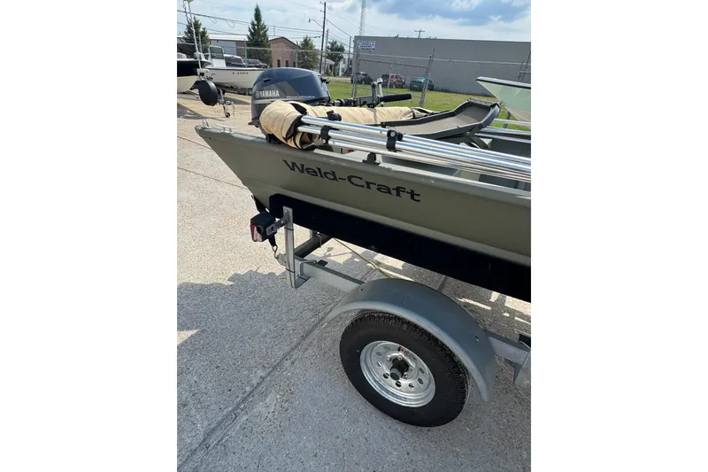 Slide: The Image of 2021 Weldcraft 15 boat on trailer with Yamaha motor, parked outdoors. - 19