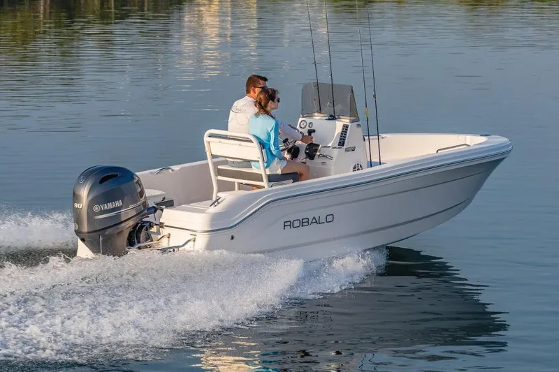 Slide: The Image of 2026 Robalo R160 Center Console boat displayed in showroom, featuring sleek blue design. - 2