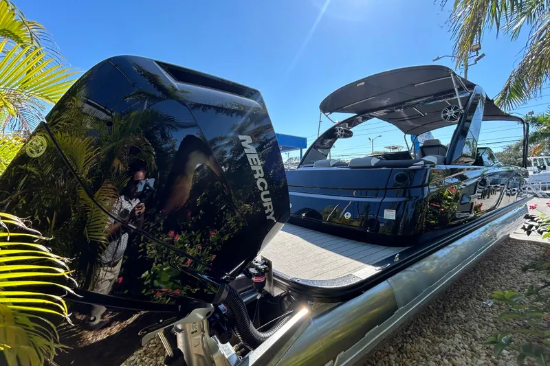 Slide: The Image of 2026 Avalon Excalibur 27-Foot boat with Mercury engine, sleek design, and canopy under clear sky. - 5