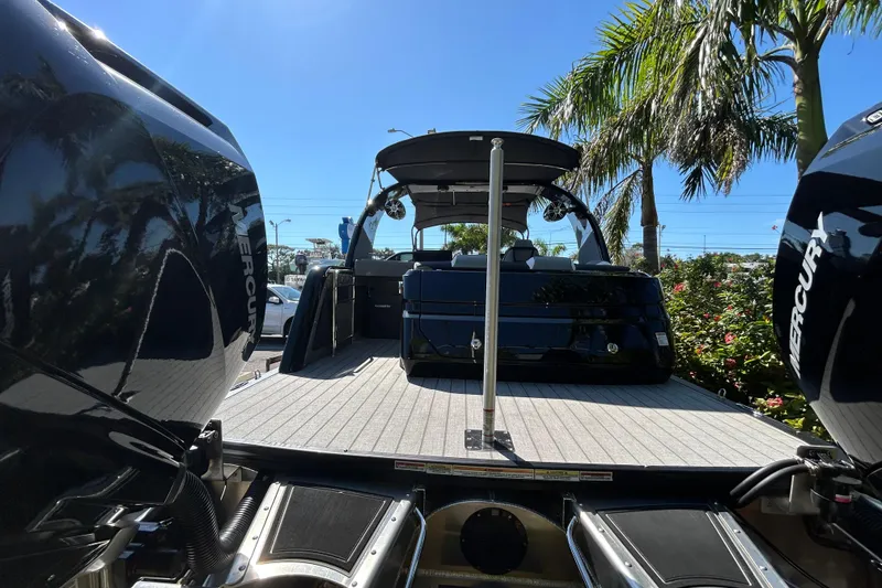 Slide: The Image of 2026 Avalon Excalibur 27-Foot boat with Mercury engines, docked under palm trees. - 6