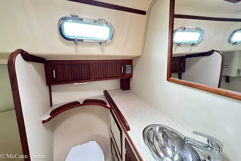 Slide: The Image of 2010 Island Packet Estero yacht bathroom with sink, mirror, and wooden cabinetry. - 22