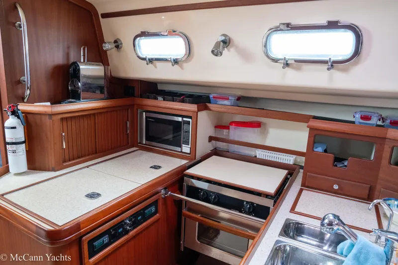 Slide: The Image of 2010 Island Packet Estero yacht kitchen with wood cabinetry, microwave, and stainless steel sink. - 46