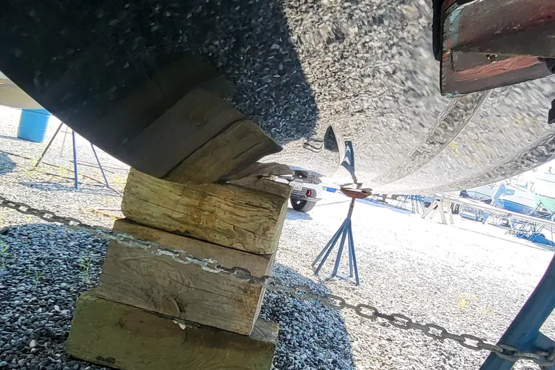 Slide: The Image of 2023 Tigé Z3 boat hull supported by wooden blocks and chains in a boatyard. - 13