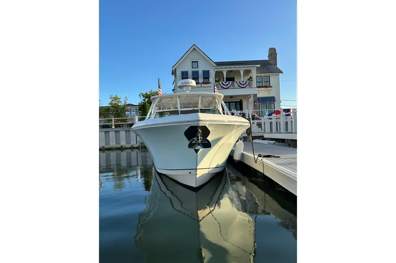 Slide: The Image of 2016 Sailfish 325 DC boat docked near a charming waterfront house. - 1