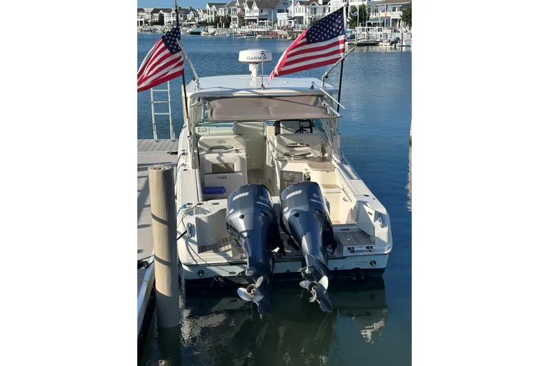 Slide: The Image of 2016 Sailfish 325 DC boat docked with twin outboard motors and American flags. - 3