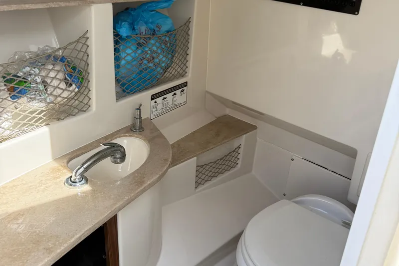 Slide: The Image of 2016 Sailfish 325 DC boat bathroom with sink, storage nets, and toilet. - 5