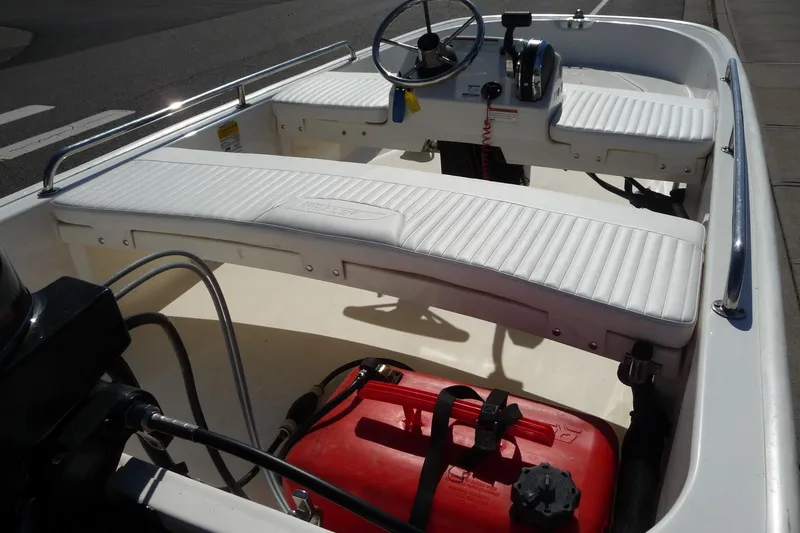 Slide: The Image of 2018 Boston Whaler 110 Sport boat interior with white seating and steering console. - 10