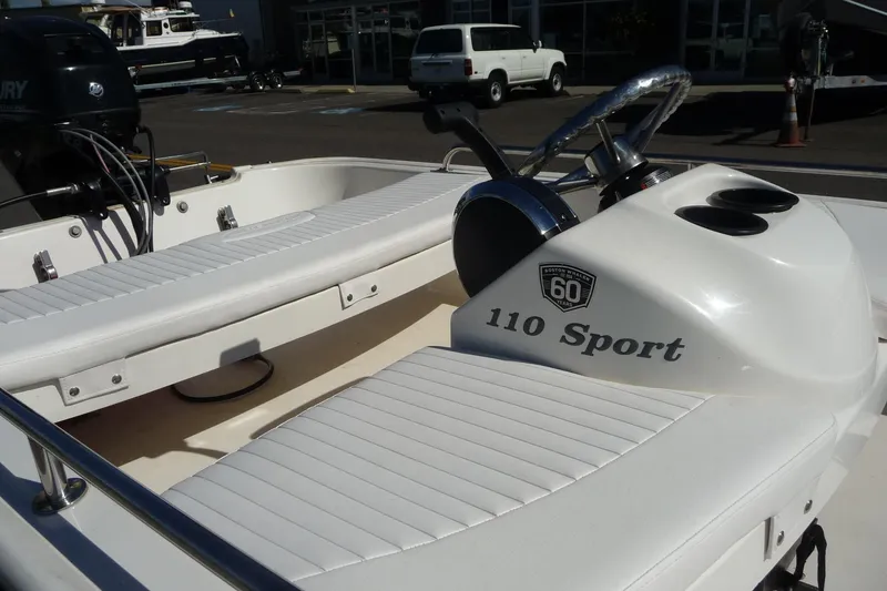 Slide: The Image of 2018 Boston Whaler 110 Sport boat interior with steering wheel and seating. - 4