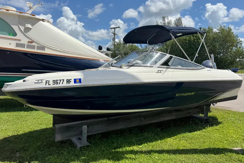 The Image of 2017 Stingray 204 LR boat on display, parked on grass under a sunny sky. - 0