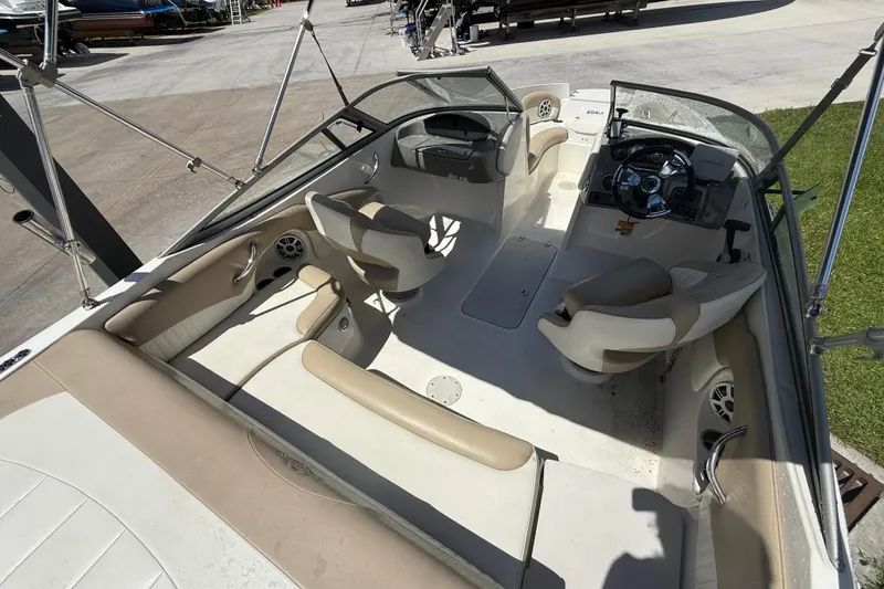 Slide: The Image of 2017 Stingray 204 LR boat interior with beige seating and steering console. - 18
