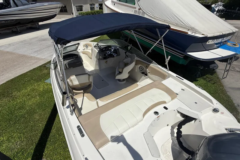 Slide: The Image of 2017 Stingray 204 LR boat with beige interior and blue canopy, parked on grass. - 19