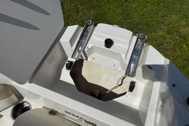 Slide: The Image of 2017 Stingray 204 LR boat compartment with open hatch and rope, on grassy background. - 22