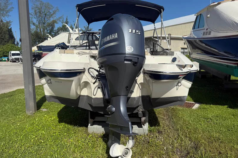 Slide: The Image of 2017 Stingray 204 LR boat with Yamaha 115 outboard motor, parked on grass. - 4