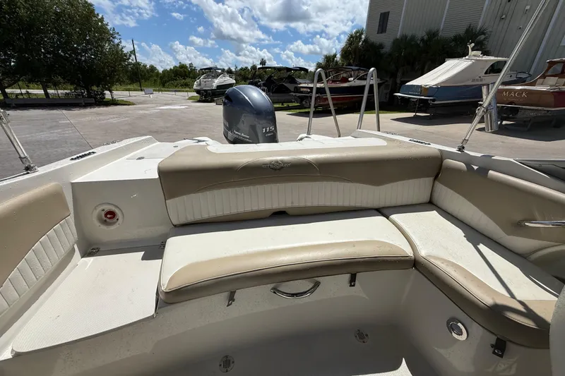 Slide: The Image of 2017 Stingray 204 LR boat interior with seating, parked outdoors under a sunny sky. - 6