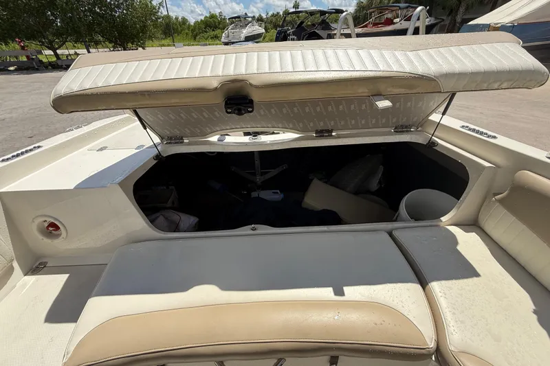 Slide: The Image of 2017 Stingray 204 LR boat with open storage compartment, beige seating, and sunny outdoor setting. - 8
