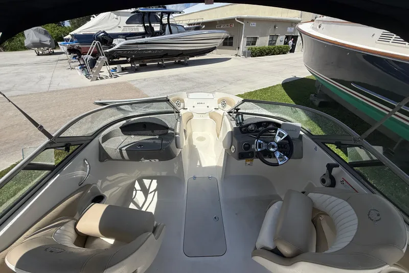 Slide: The Image of 2017 Stingray 204 LR boat interior with steering wheel and seating, docked near other boats. - 9