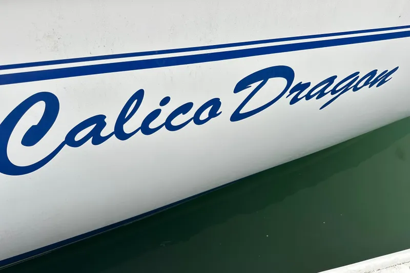 Slide: The Image of Catalina 320 sailboat named "Calico Dragon" with blue lettering on the hull. - 13