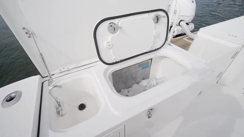 Slide: The Image of Open storage compartment on 2026 World Cat 400CC-X boat, featuring sink and ice chest. - 32