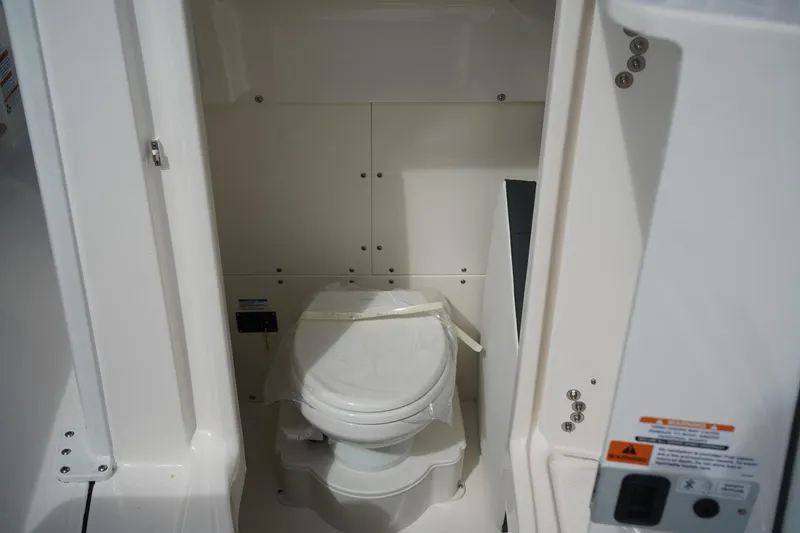 Slide: The Image of 2026 Robalo R250 Center Console boat interior with a compact marine toilet. - 37
