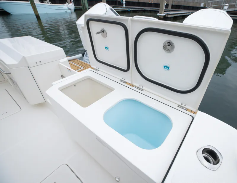 Slide: The Image of 2026 World Cat 400DC-X Island boat with open storage compartments at the dock. - 7