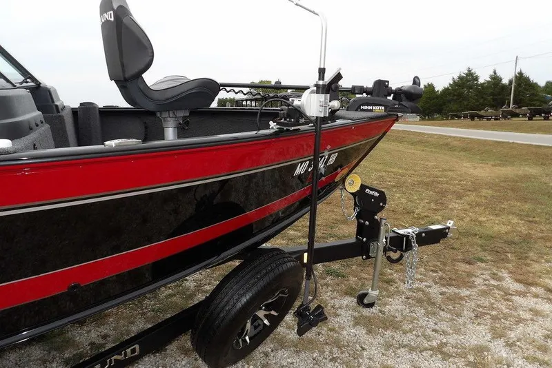 Slide: The Image of 2022 Lund 1875 Impact Sport boat on trailer, red and black design, parked on gravel. - 35
