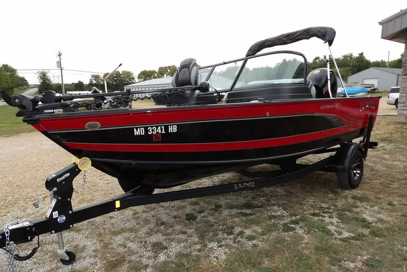 Slide: The Image of 2022 Lund 1875 Impact Sport boat on trailer, red and black design, parked outdoors. - 7