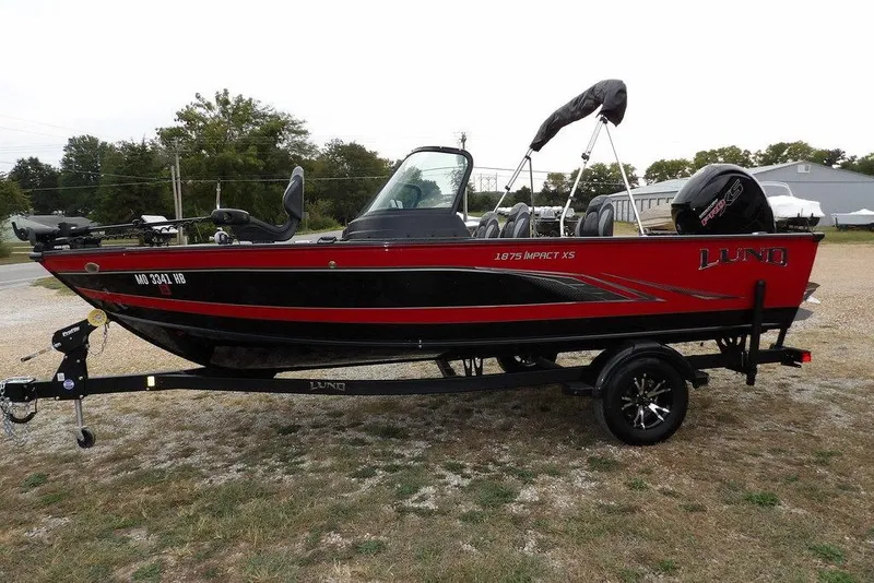 Slide: The Image of 2022 Lund 1875 Impact Sport boat on trailer, red and black design, parked outdoors. - 8