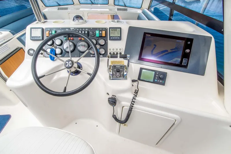Slide: The Image of Control panel of 2000 Riviera 48 Enclosed Flybridge with steering wheel and navigation equipment. - 16