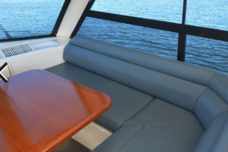 Slide: The Image of Interior of 2000 Riviera 48 Enclosed Flybridge with blue seating and wooden table. - 17