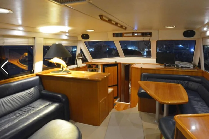 Slide: The Image of Luxurious interior of 2000 Riviera 48 Enclosed Flybridge with leather seating and wooden finishes. - 2