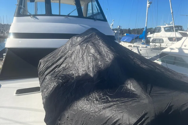 Slide: The Image of 2000 Riviera 48 Enclosed Flybridge yacht with covered equipment on deck, docked at marina. - 26