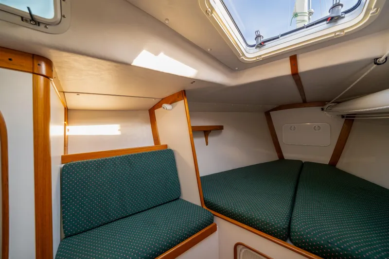 Slide: The Image of Interior cabin of 2000 J Boats J/120 sailboat with green cushioned seating and wooden accents. - 13