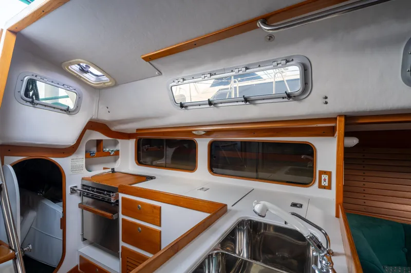 Slide: The Image of Interior of 2000 J Boats J/120 sailboat, featuring a compact kitchen with wood accents. - 15