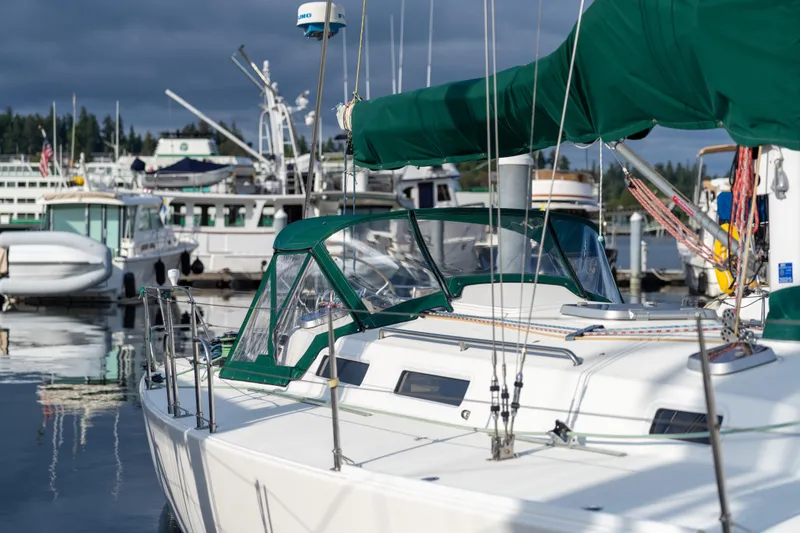 Slide: The Image of 2000 J Boats J/120 sailboat docked in a marina, featuring green canvas covers. - 2