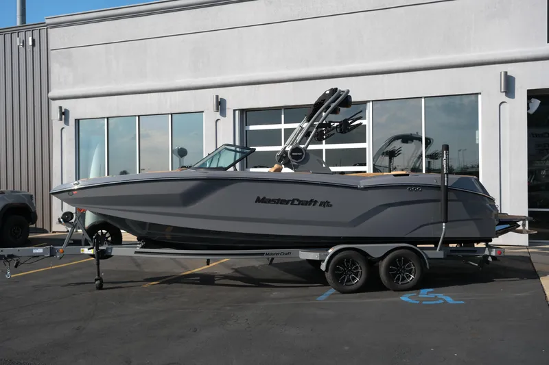 Slide: The Image of 2026 MasterCraft NXT24 boat on trailer, parked outside a building. - 33