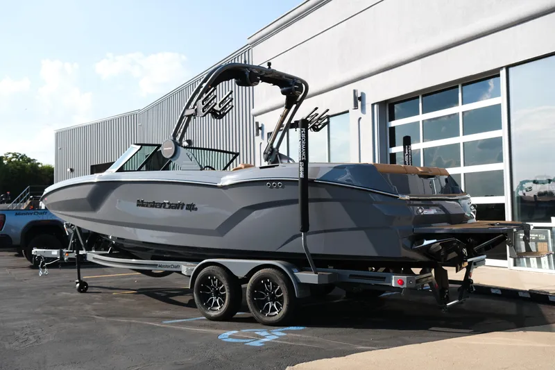 Slide: The Image of 2026 MasterCraft NXT24 boat on trailer, parked outside a modern building. - 4