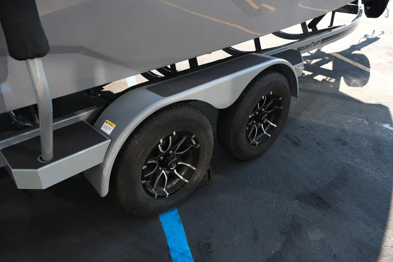 Slide: The Image of Trailer wheels of a 2026 MasterCraft NXT24 boat on a parking lot. - 9
