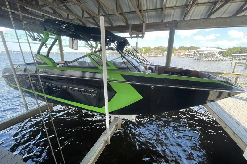 Slide: The Image of 2016 Nautique Super Air Nautique G23 Coastal Edition boat in dock, black and green design. - 3