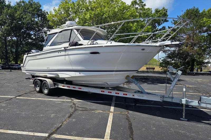 The Image of 2026 Cutwater C-248 Coupe boat on trailer in parking lot, surrounded by trees. - 1