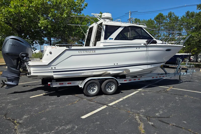 Slide: The Image of 2026 Cutwater C-248 Coupe boat on trailer, parked in a lot with trees in the background. - 3