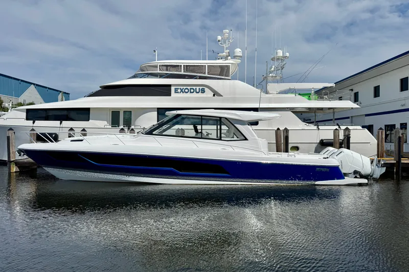 Slide: The Image of 2026 Intrepid 50 Evolution yacht docked beside a larger vessel. - 1