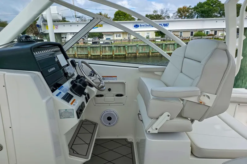 Slide: The Image of 2024 World Cat 296 DC boat interior with seating and coolers on a calm lake. - 15