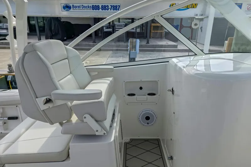 Slide: The Image of 2024 World Cat 296 DC boat interior with seating and rod holders on a calm lake. - 16