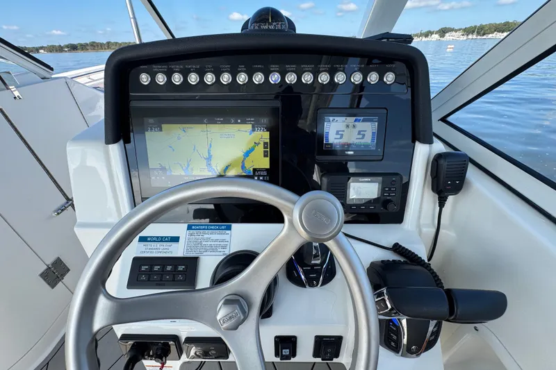 Slide: The Image of 2024 World Cat 296 DC helm with navigation screens and controls on a calm water backdrop. - 24