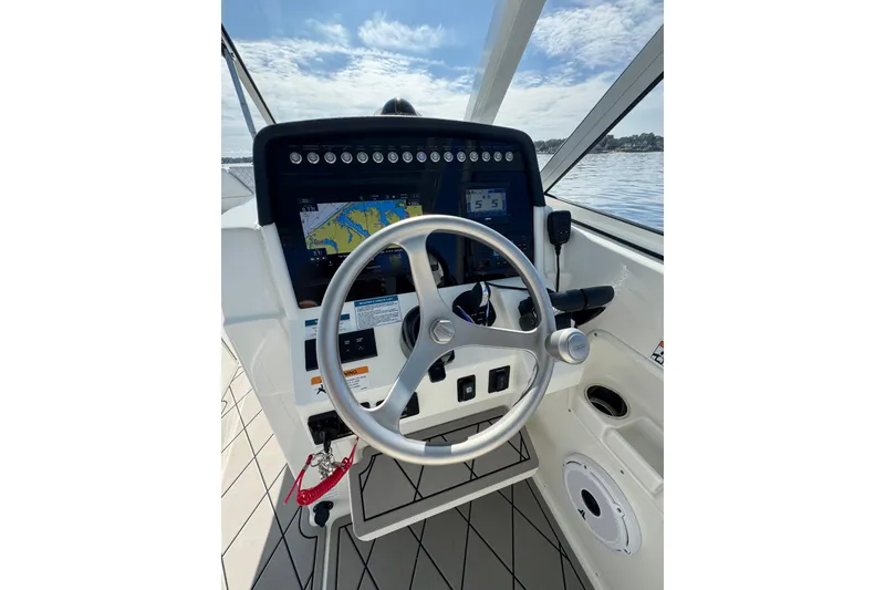 Slide: The Image of 2024 World Cat 296 DC helm with navigation display and steering wheel on open water. - 25