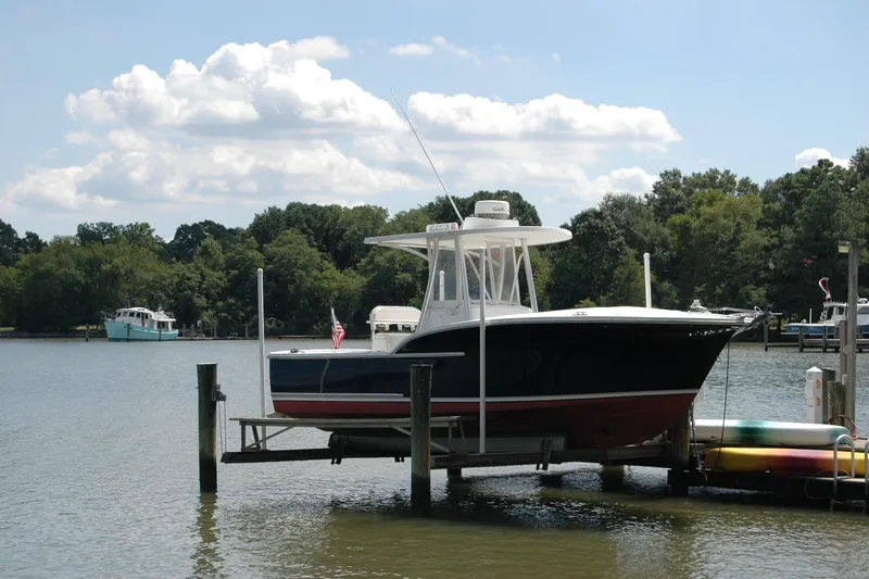 The Image of 2013 Composite Yacht 26 on lift by serene lake with trees and boats. - 0